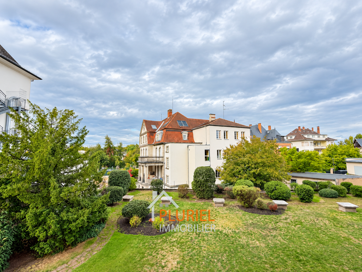 Villa élégante au jardin paysager sous ciel nuageux