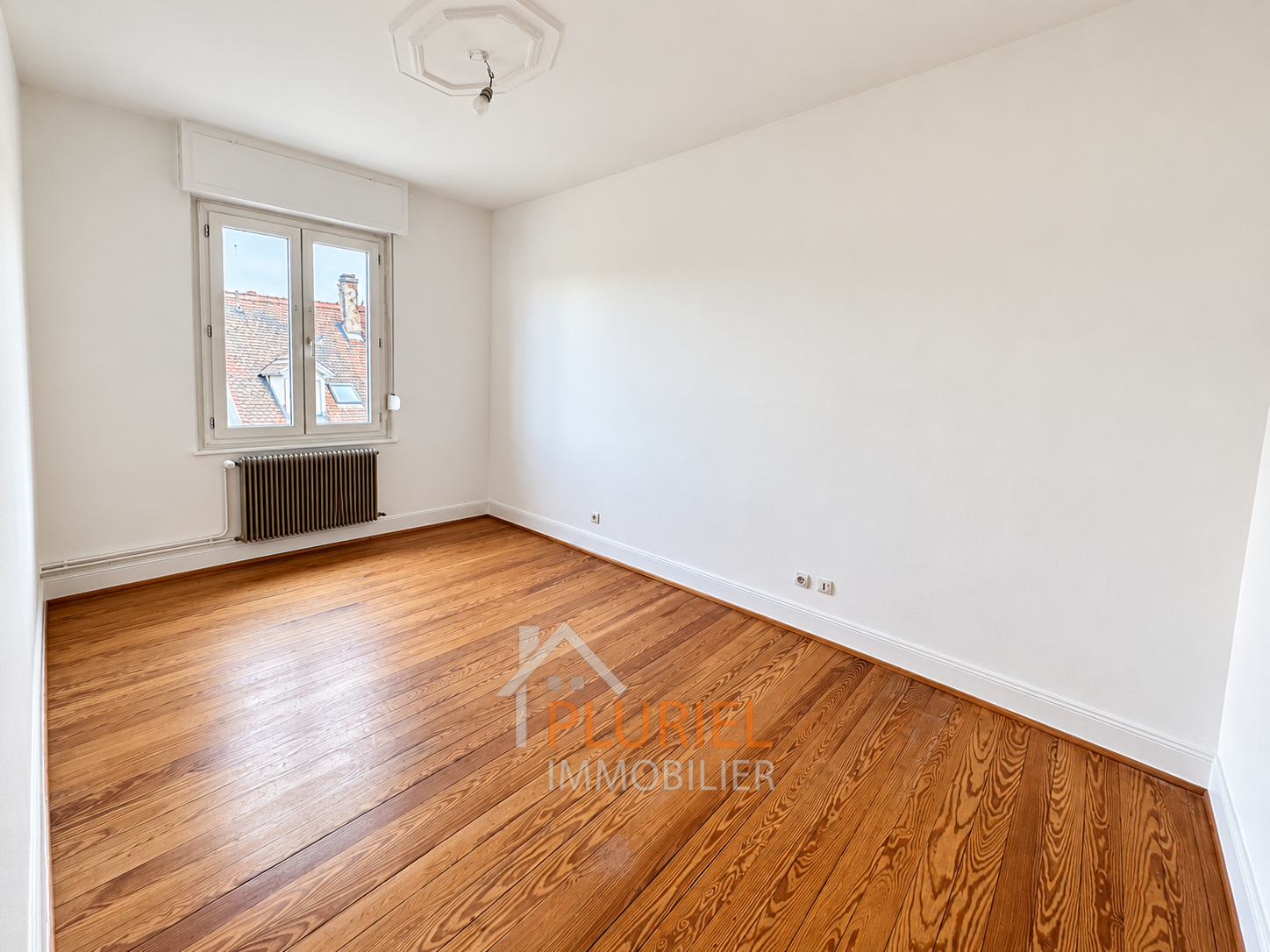 Chambre vide lumineuse au parquet chaleureux