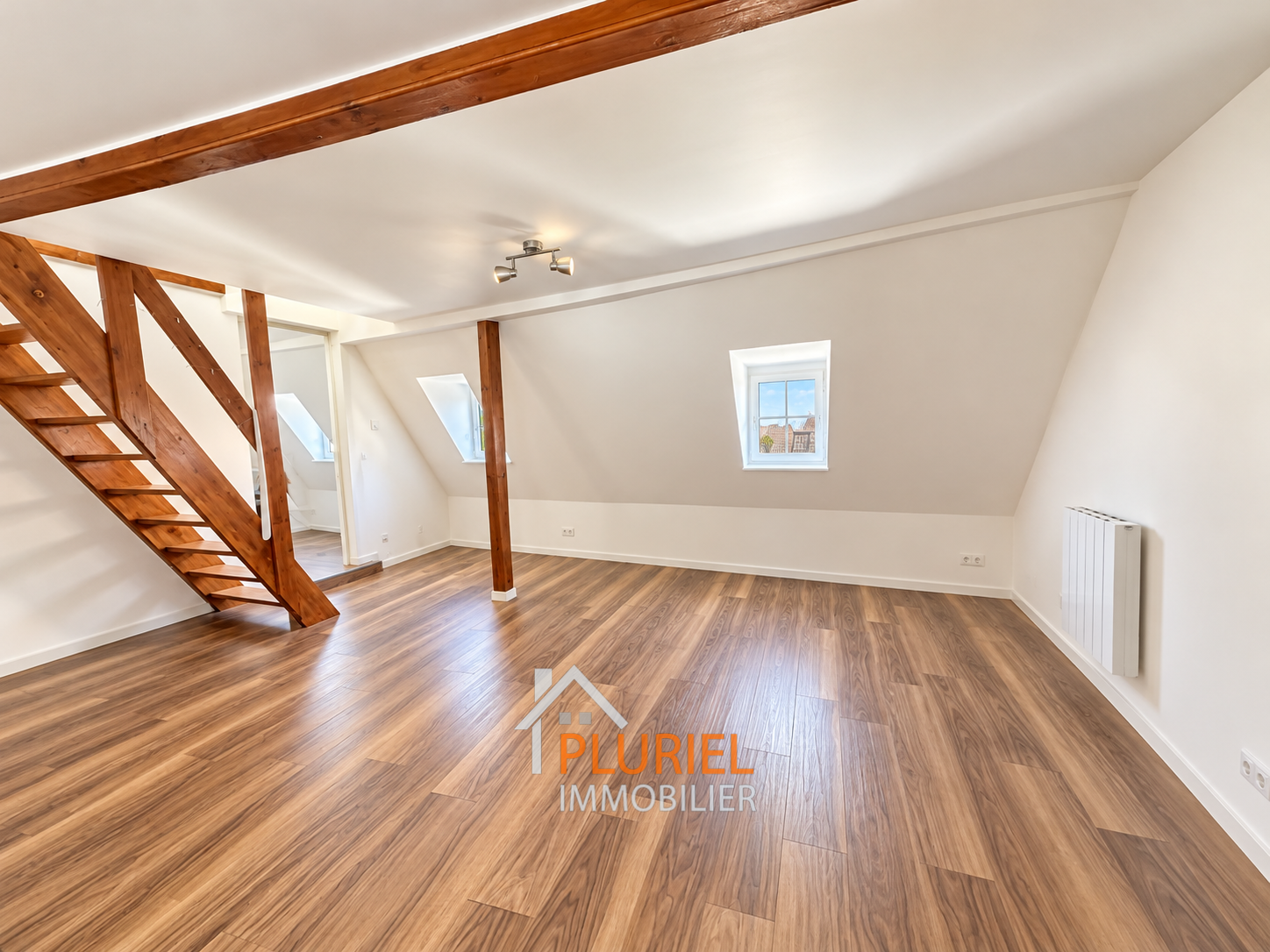 Loft mansardé lumineux aux poutres apparentes