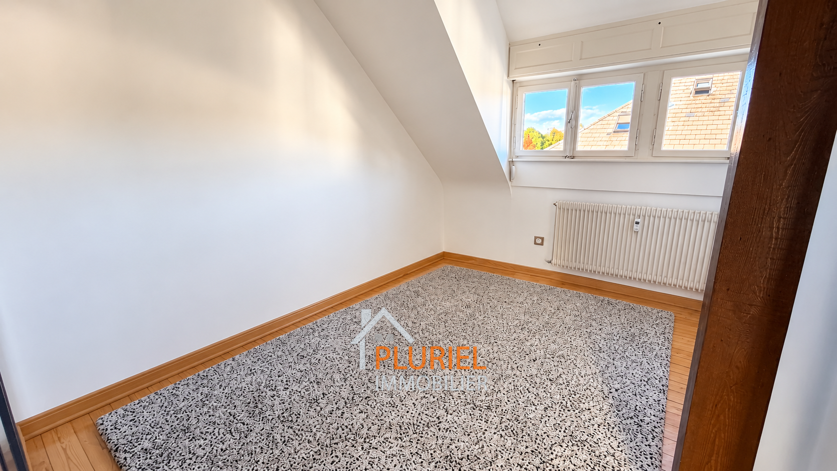 Pièce mansardée lumineuse avec tapis gris